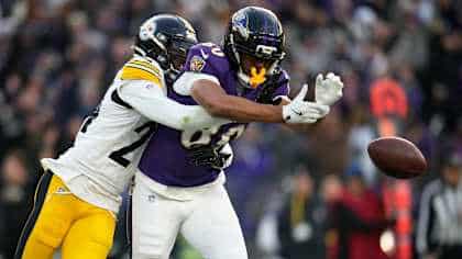 A Pittsburgh Steelers defender breaks up a pass intended for a Baltimore Ravens receiver during a football game.